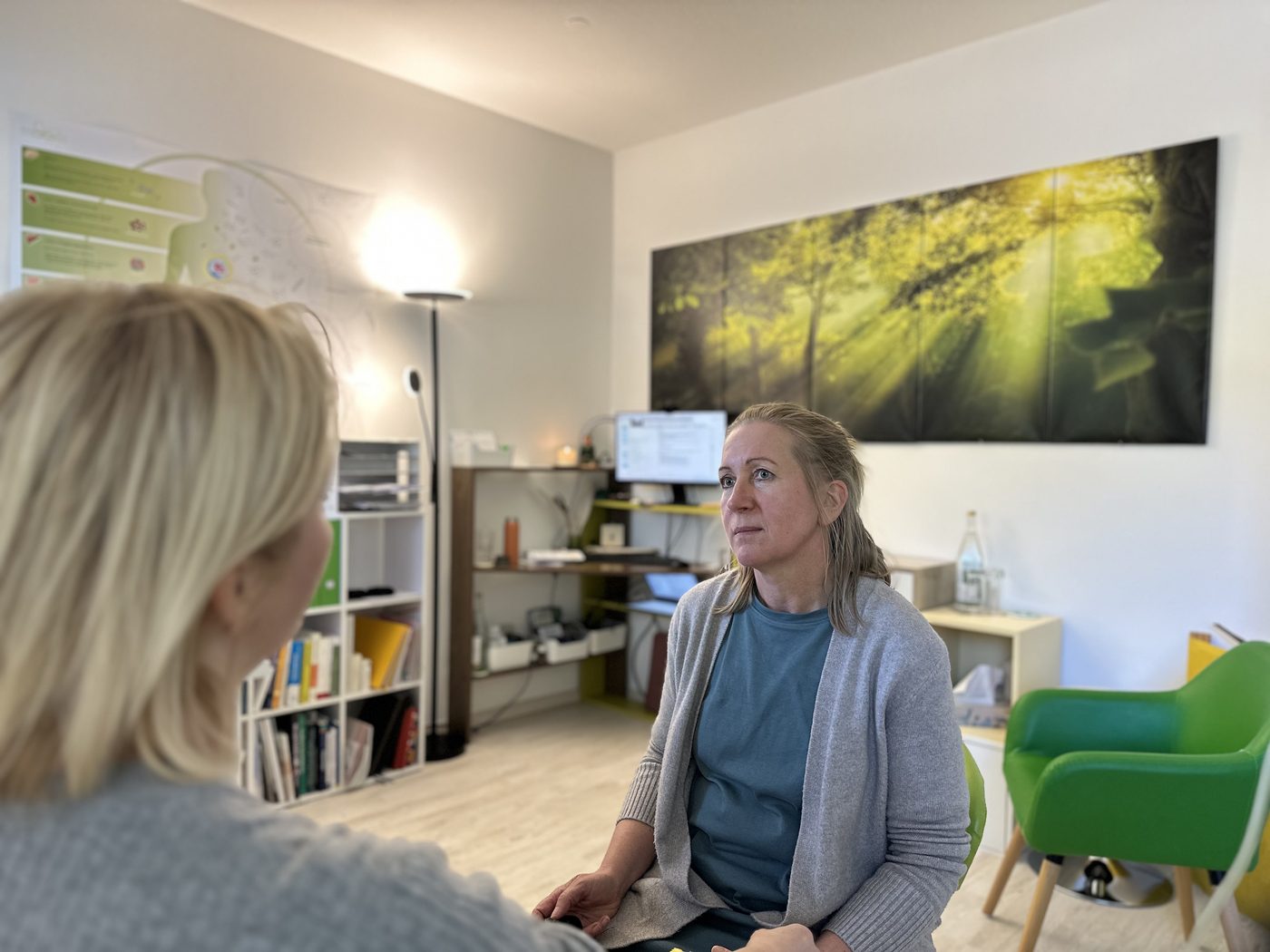 Delia Gröninger sitzt im Behandlungsraum einer Patientin gegenüber und hört ihr aufmerksam zu. Die Patientin ist von hinten zu sehen.